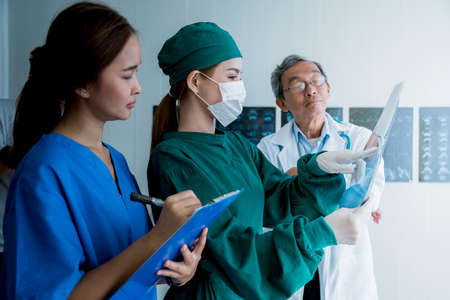 asian doctor team examine x-ray film of patient analysis to find bext solution for operation and...