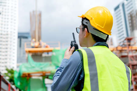 back view of professional engineer asian male safety helmet manage control constuction site with expertise workingの写真素材