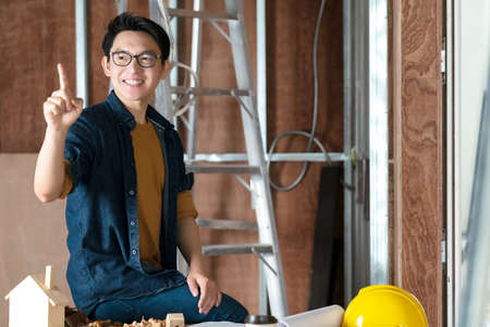 young asian carpenter hand draw in the air with copyspace for your text with background of house...