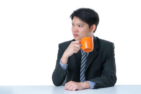 smart business asian man in suit sit at desk drink hot coffee white backgroundの写真素材
