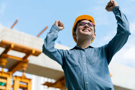 successful handup smart asian engineer manager with safety uniform checking site construction with steel and concrete structure backgroundの写真素材
