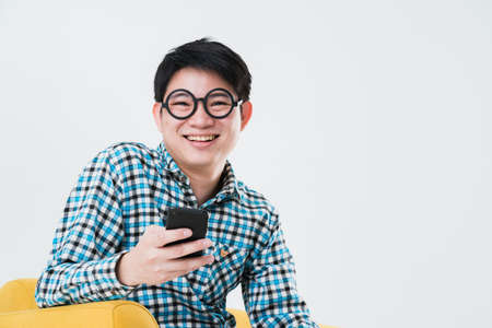 busy asian man tshirt hand hold smartphone on sofaの写真素材