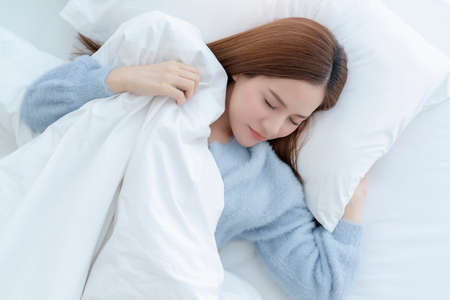 beautiful asian woman blue sweater lay done on white bed casual lifestyle morning time weekend...