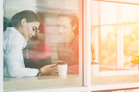 two attractive caucasian gossip and conversation after work near window and desk office backgroundの写真素材