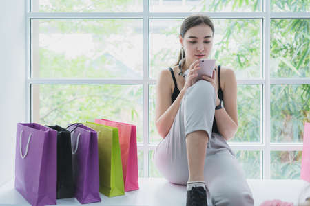 two beautiful caucasian female enjoy shopping online with full of bags smartphone and credit card...