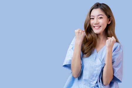 happiness cheerful strong freshness asian female patient in hospital uniform get well stay strong after illness from coronavirus flu hand gesture fight facial expression blue backgroundの写真素材
