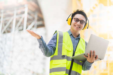 smart asian male professional civil engineer hand hold laptop site construction check with...