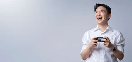 Portrait of a young attractive asian man playing video console games on joy stick with success...