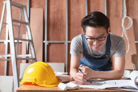 asian attractive glasses interior designer working at house site renovation construction progress...
