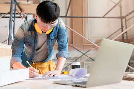 asian engineer male with uniform working with laptop and home mockup model analysis construction...