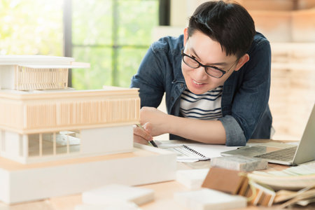 smart smile asian architect interior designer working house design project with home mockup and blueprint paper and material chart sample with enthusiasm focus and confident with garden backgroundの写真素材