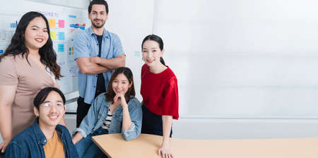 Smart asian startup small entrepreneur  standing confident portrait with  friends partner casual meeting brainstorm with white board and business financce paper chart anslysis in office backgroundの写真素材