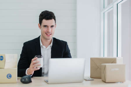 attractive caucasian businessman in delivery business working with laptop office background