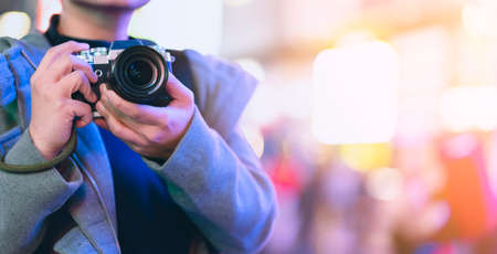 asian female traveller smile happiness hand hold mirrorless camera enjoy nightlife lifestyle tourost with light bokeh and crowd of people blur background in winter season close up banner size;の写真素材