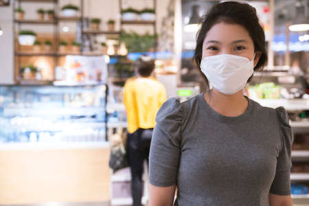 new normal after covid epidemic  young business asian female wear facial protection mask walking in center square department store mall new lifestyle after spread of corona virus covid-19の写真素材