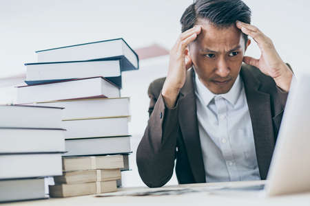 business asian man focus and thinking with money and project on table color tone imageの写真素材