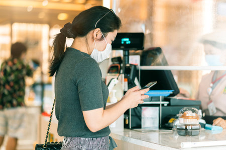 new normal after covid epidemic asian female payment progress buy scaning app by smarthine cashless and touchless new lifestyle shopping in department store cashier counterの写真素材
