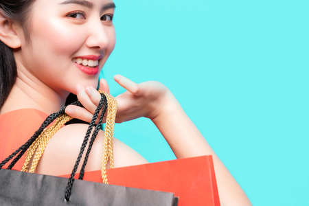 attractive beautiful asian woman red dress hand hold shopping bag big smile with happiness and joyful color backgroundの写真素材