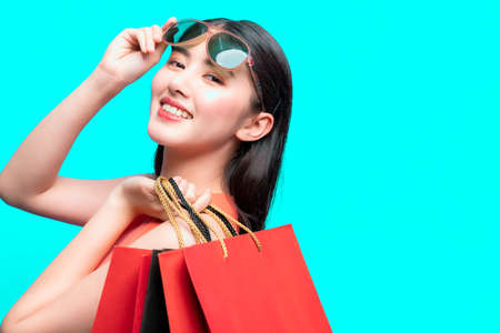 attractive beautiful asian woman red dress hand hold shopping bag big smile with happiness and joyful color backgroundの写真素材