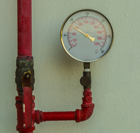 Water pressure gauge meter installed on a red pipeの写真素材