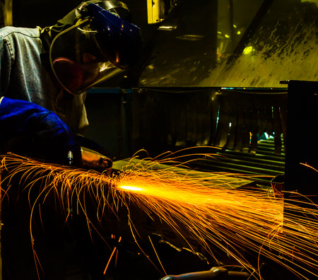 worker in automotive industry movement work grinding parts with sparks