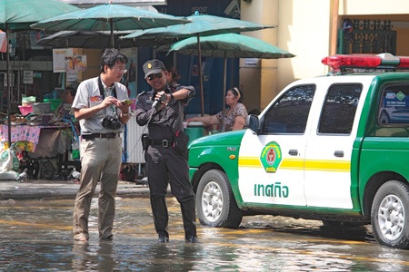 BANGKOK - october 29: Japanese Reporter and Thai municipal official  with the largest flood  in 50 years in the capital on october 29, 2011 in Bangkok, Thailand.のeditorial素材