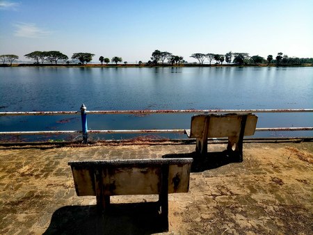 Two outdoor stone bench on the cement floor on the lakeside views from the public park.の写真素材