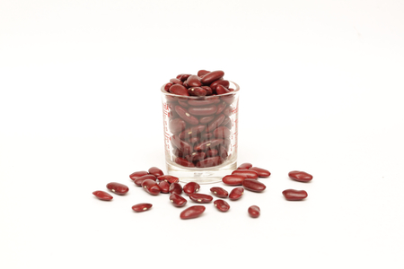 isolated measuring glass cup contains red kidney bean on white backgroundの写真素材