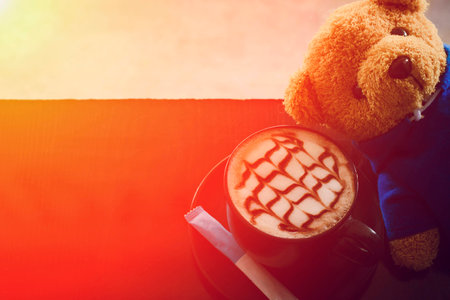 Cup of coffee next to Teddy Bear light orange.の写真素材