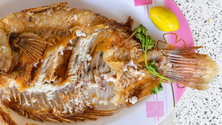 Fried fish, eaten, placed on a plate.