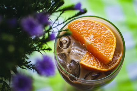 A glass of milk tea decorated with oranges.