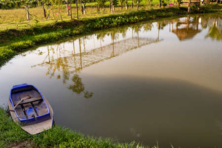 A blue boat in the pond in front of the house