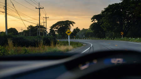 Drive the car in a curve during the evening with a traffic sign.の写真素材