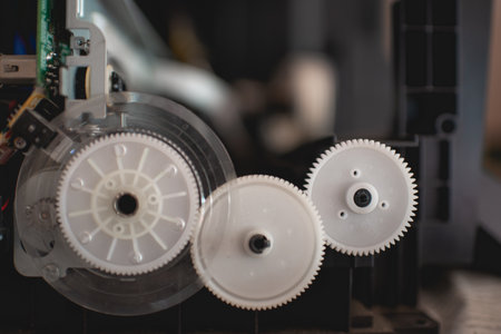 The printer that has been disassembled for repairs has colored gears and internal parts of the white...