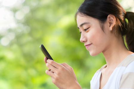 Asian woman typing  on smartphoneの写真素材