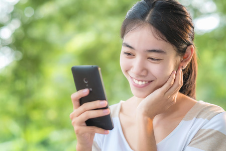 Asian woman using internet in her smart phone at outdoor in parkの写真素材