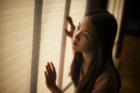 woman standing by the window Feeling sadの写真素材