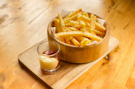 French fries in wooden bowl with Ketchup and mayonnaise