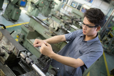 Men are working with machines . Man set up with a steel lathe.