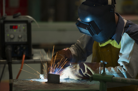 man welding steel by skill.Men wear protective clothing during work.