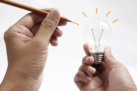 hand with a pen drawing light bulbの写真素材