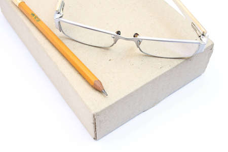 notebook glasses and yellow pencil on box