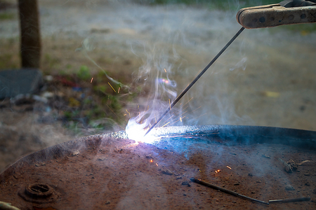 Electricity welder steel cutting old oil tank With welding wire, Purple smoke and light
