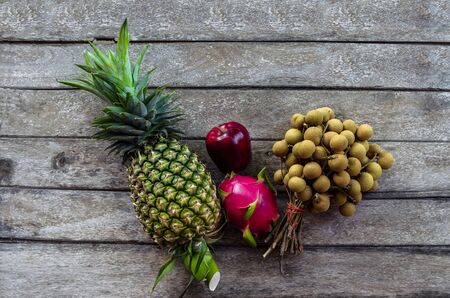 Close Up Mix fruit of ripe longans pineapple and apple on an old wooden background with nature lightの写真素材