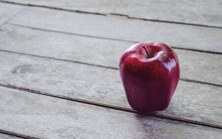 Red apple on vintage wooden background with nature lightの写真素材
