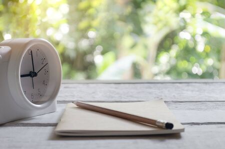Class room in nature background with Brown books, pencils, alarm clock, on a white wooden table with...