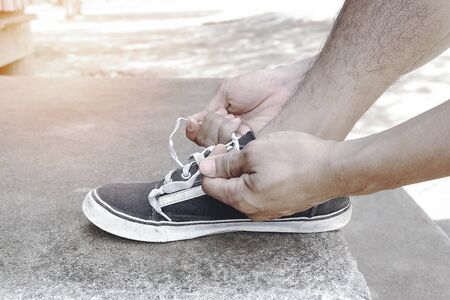 Male athletes tie a shoelace to prepare for exercise by the run. Exercise is a healthy exercise.の写真素材
