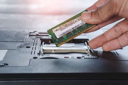 Repairman fixing and repair memory ram or setup hardware for the computer on laptop motherboard with his handsの写真素材