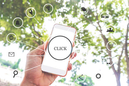 Concept icon of social media on a phone with a white mockup screen a man holding a smartphone. Concept technology internet iot social media with green nature backgroundの写真素材