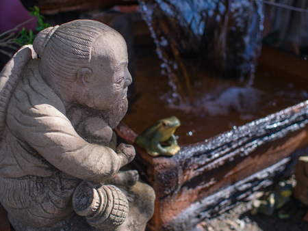 Doll Mortar Old Man Sitting Beside an Artificial Waterfallの写真素材
